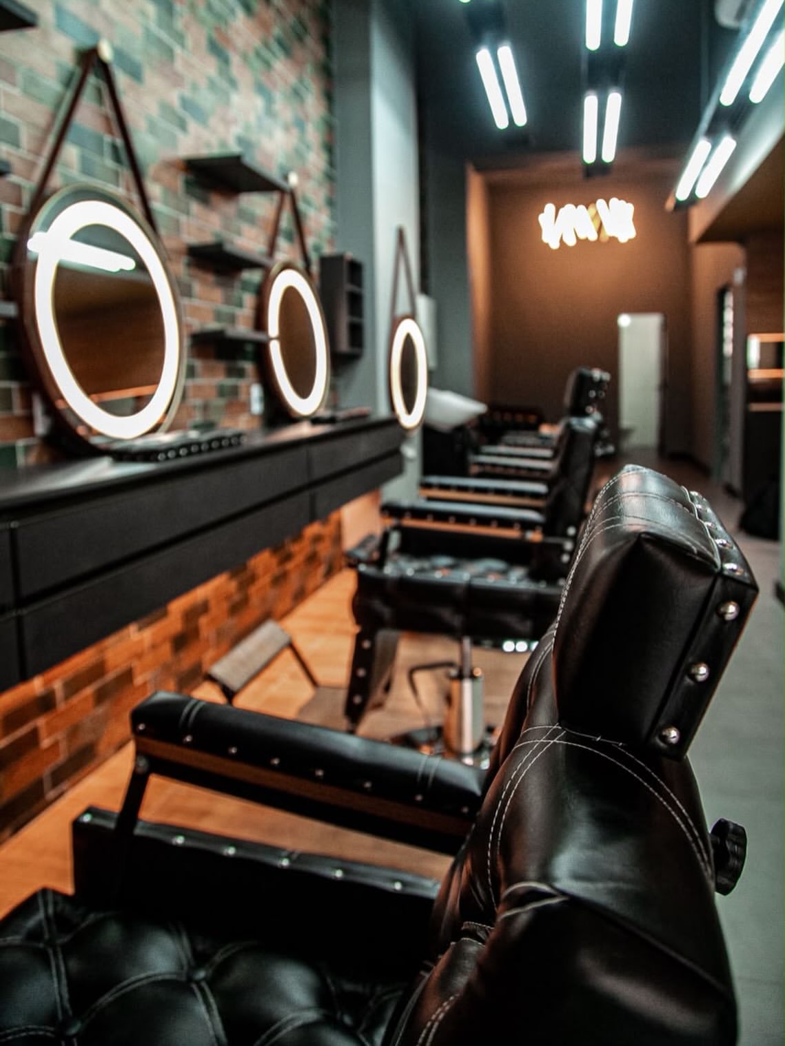 Interior da barbearia com cadeiras e espelhos redondos